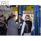 -- AMITEC 2004 --- Auf dem Stand von Schumann Werkstatt-Technik. Olaf Wiesenmller (mitte) von SLIFT Hebezeuge ber die Vorteile einer SLIFT 2-Sulenbhne.  